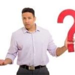 Man in a light purple shirt holding a large red question mark, symbolizing inquiries about HVAC system selection and professional guidance.