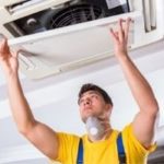 HVAC technician inspecting ceiling-mounted air conditioning unit, emphasizing maintenance and repair services by Mid Florida A/C.