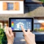 Person using a tablet to control home HVAC settings, with a house in the background, representing digital thermostat technology and home comfort solutions.