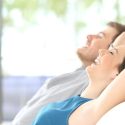 Couple relaxing indoors, enjoying comfortable air quality, emphasizing the importance of HVAC services for a pleasant home environment.