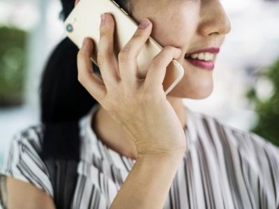 Woman smiling while talking on a smartphone, representing communication for air conditioning repair services.