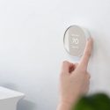 Hand adjusting a smart thermostat on a wall, emphasizing modern HVAC technology and home comfort management.