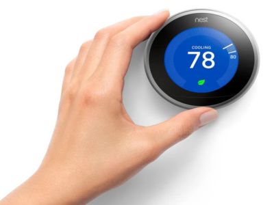 Hand adjusting a Nest thermostat displaying a cooling temperature of 78 degrees Fahrenheit, emphasizing energy efficiency and home comfort.