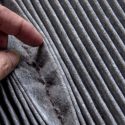 Hand inspecting a dirty air filter, highlighting the importance of regular air filter replacement for improving indoor air quality in HVAC systems.