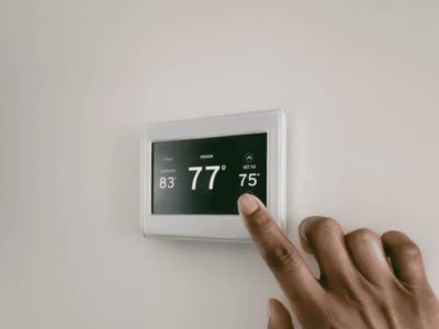 Hand adjusting a digital thermostat displaying temperature settings, relevant to troubleshooting heating issues and ensuring indoor comfort.