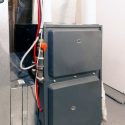 Gray heater unit with visible pipes and connections, illustrating essential HVAC maintenance for optimal home heating efficiency.