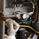 Technician repairing a heating system, focusing on internal components and wiring, highlighting the importance of professional HVAC services for home comfort.