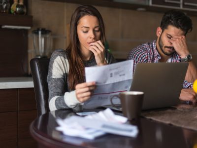 Couple reviewing high energy bills with concern, highlighting financial stress related to rising heating costs and the importance of addressing heater inefficiencies.